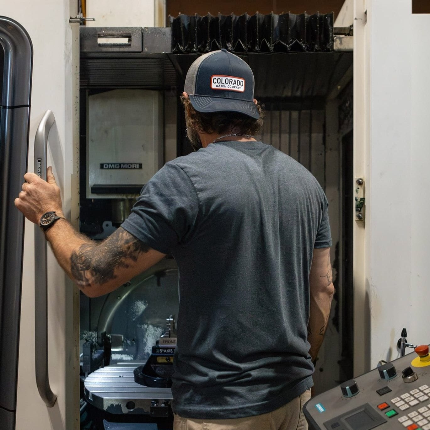 Josh at CNC machine with Colorado Watch Company Hat and Shirt
